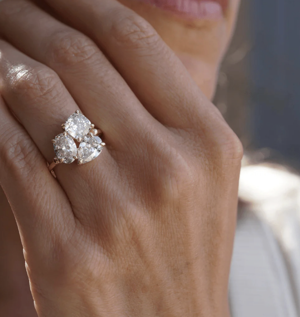 Three-stone diamond ring with mixed cuts worn on hand in soft light