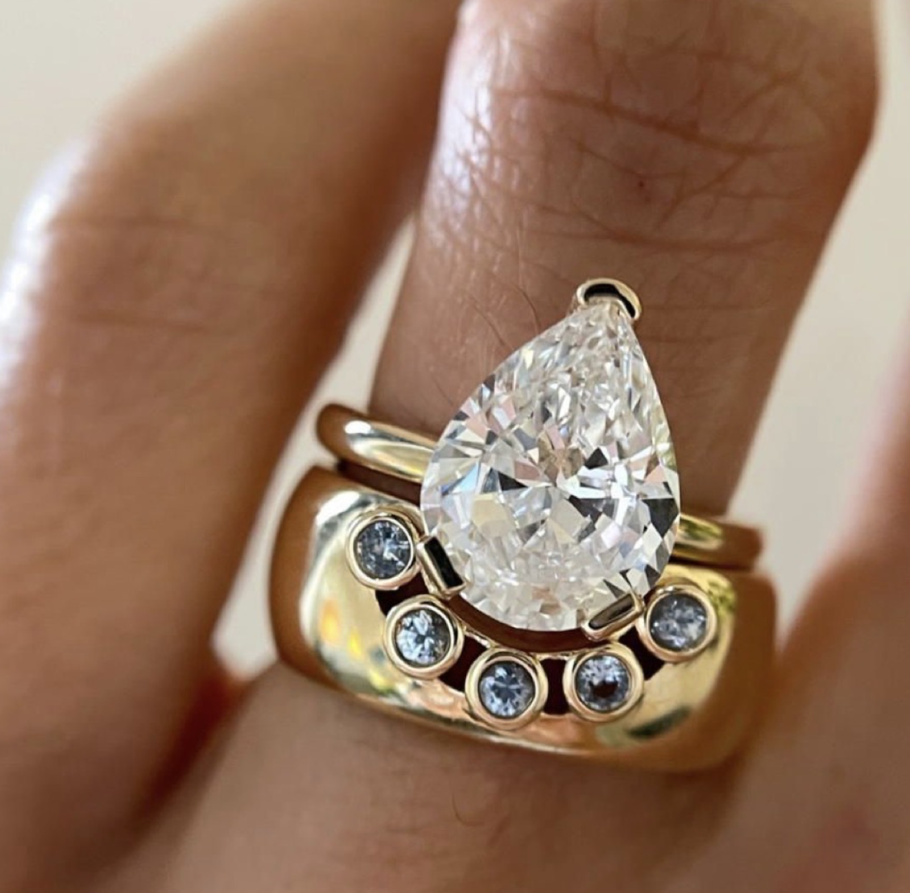 Pear-shaped diamond ring paired with a curved diamond-accent gold band